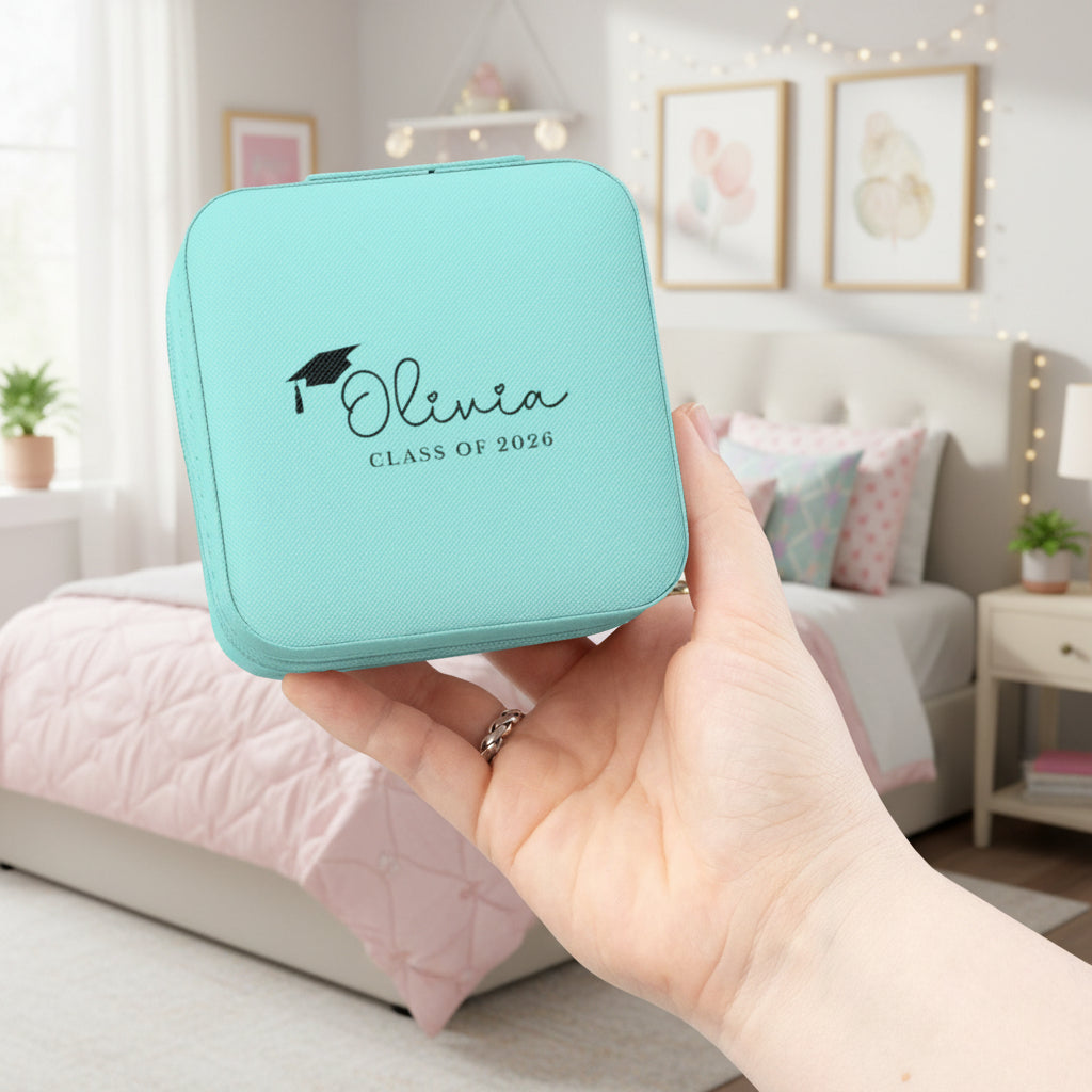 Turquoise jewelry box with 'Olivia Class of 2026' text held in a hand against a white background